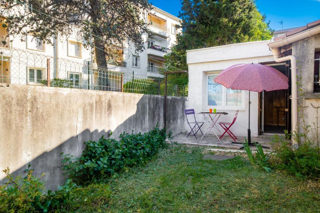 um pátio com uma mesa com um guarda-chuva roxo em Charming Studio of 17 m with garden Montpellier em Montpellier