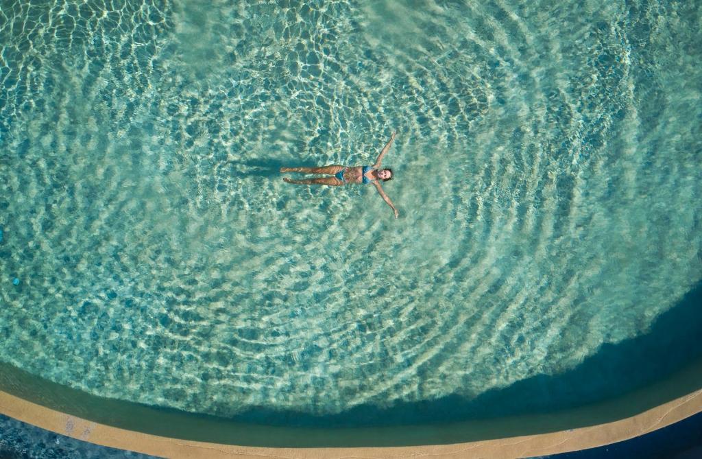 a person swimming in the water in the ocean at Danae Suites Santorini in Oia