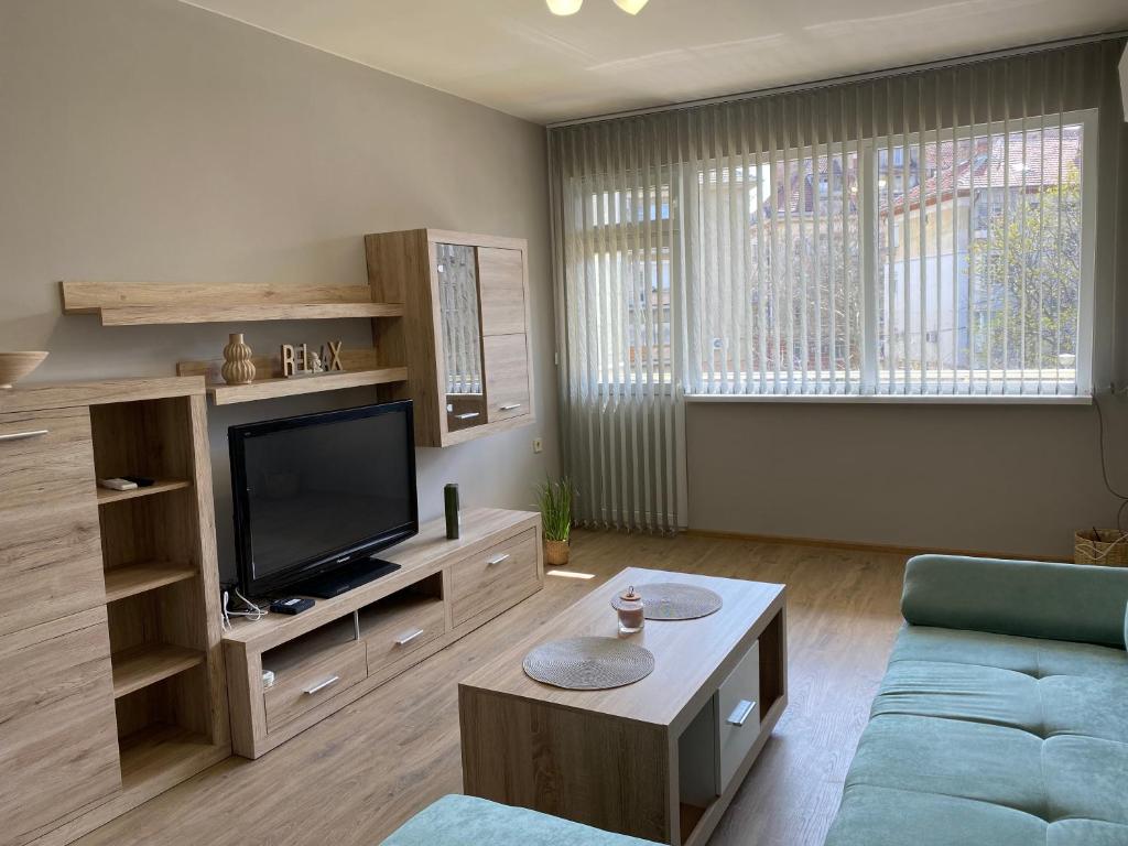 uma sala de estar com um sofá e uma televisão em Апартамент за гости ДИГЕНА em Kazanluk
