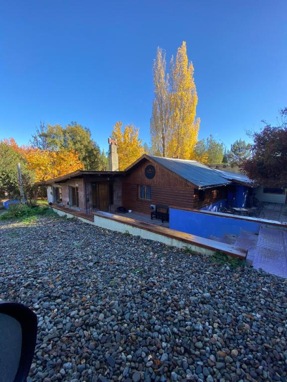 a building on a gravel road next to a house at Cuatro Cerros Hostel in San Carlos de Bariloche