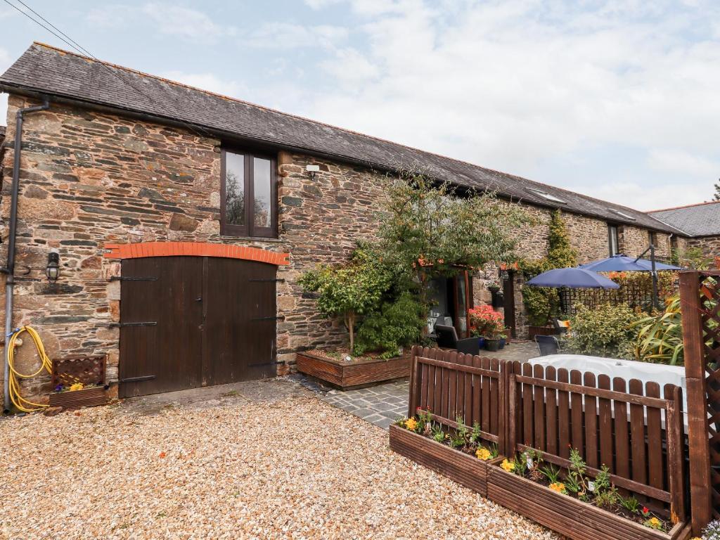 a brick house with a wooden gate and a patio at Foxglove Barn in South Brent