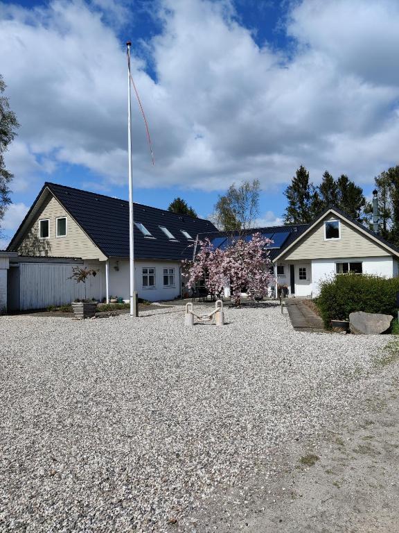 een huis met een vlaggenpaal op een grindoprit bij Rosengård in Hammel