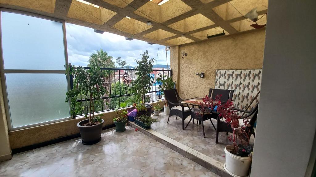 MENBi's Apartment في Kitimē: شرفة مع طاولة وكراسي والنباتات