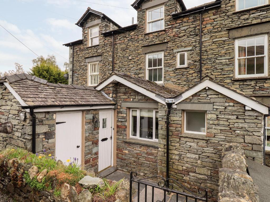 a stone house with a white garage in front of it at Holmdale in Ambleside