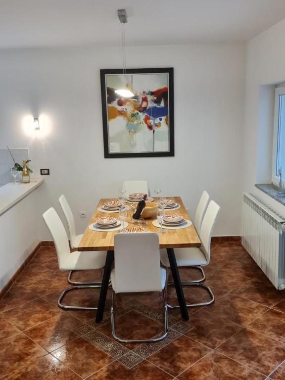 a dining room with a wooden table and white chairs at Apartment Donna Rijeka in Rijeka