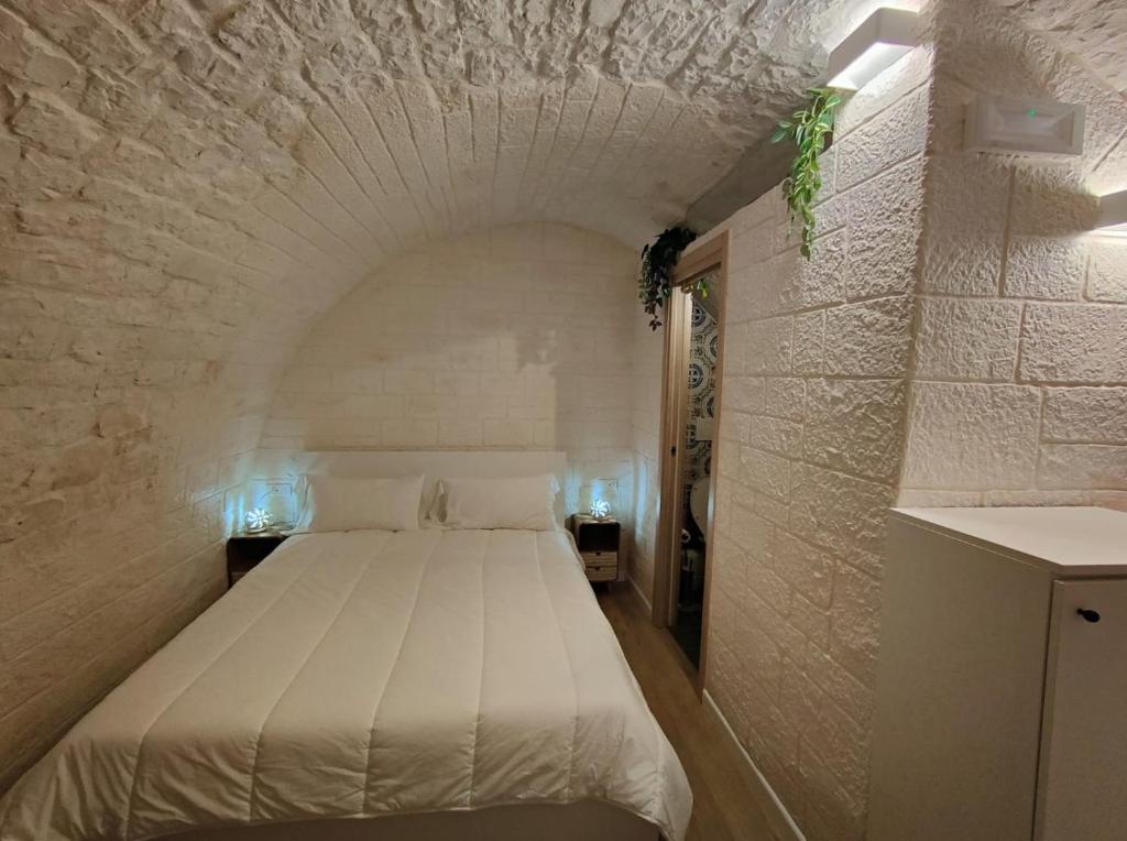 a bedroom with a white bed in a brick wall at La casetta di Ottavio in Castellana Grotte