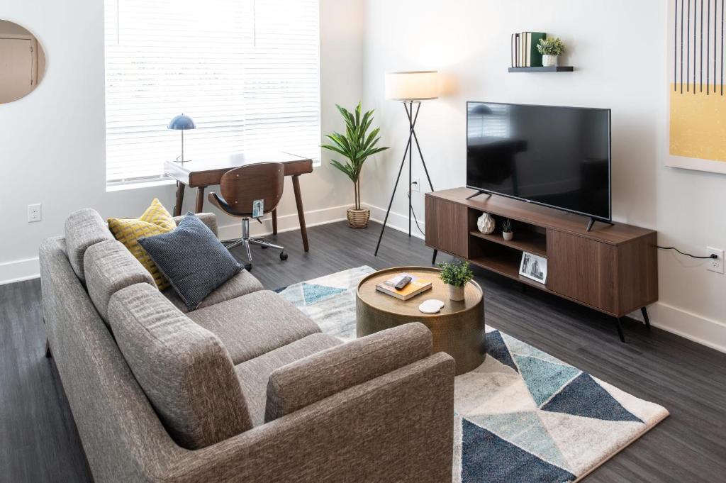 ein Wohnzimmer mit einem Sofa und einem Flachbild-TV in der Unterkunft Cozysuites l Stylish 1BR in Downtown Cincinnati in Cincinnati