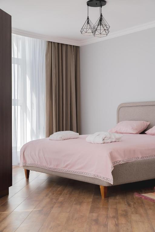 a bedroom with a bed with pink sheets and a window at 71 East Apart Hotel in Prigorodnyy
