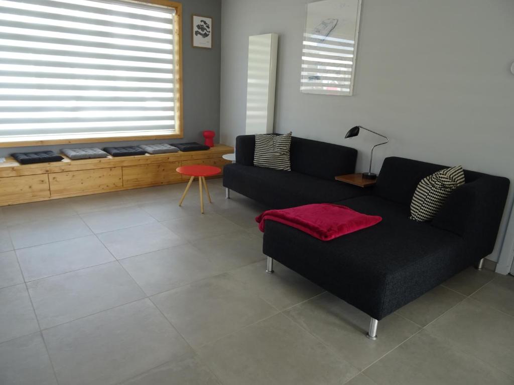 a living room with a black couch and a red stool at Kustverhuur, Dorpswoning Breskens, Boulevard 15 in Breskens