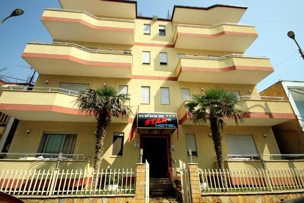 um edifício alto com palmeiras em frente em King's Star Hotel em Velipojë