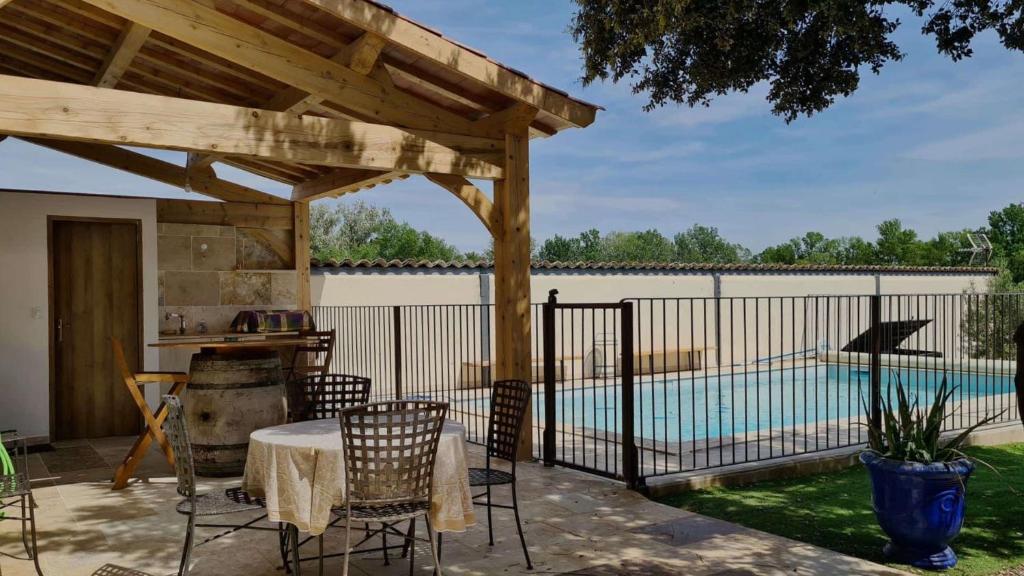 une terrasse avec une pergola en bois et une piscine dans l'établissement Mas de la Roncière, à Sorgues