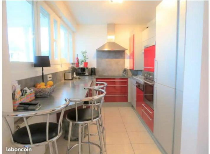 a kitchen with red cabinets and a counter with bar stools at Chambre #3 dans appartement partagé - Proche des Vosges in Thann