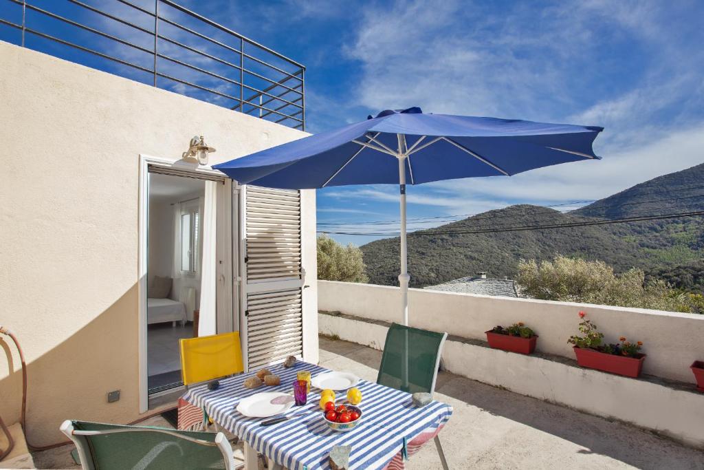 - une table avec un parasol bleu sur le balcon dans l'établissement Casa Les Oliviers, à Santa-Maria-di-Lota
