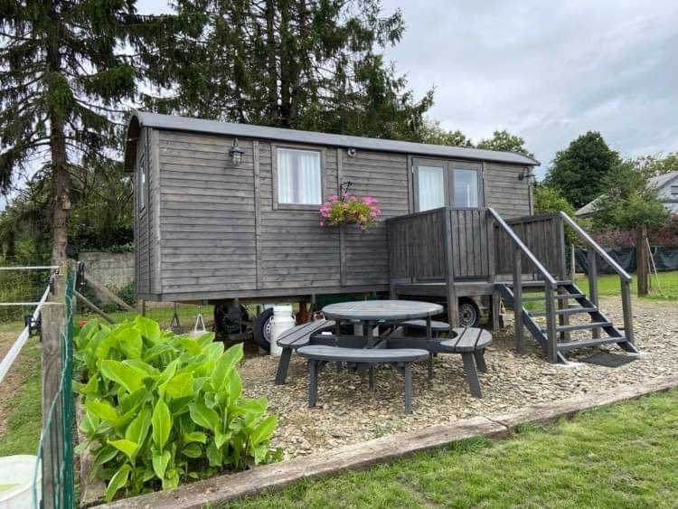 a tiny house with a picnic table and a patio at Pipowagen Monceau-en-Ardenne in Bièvre