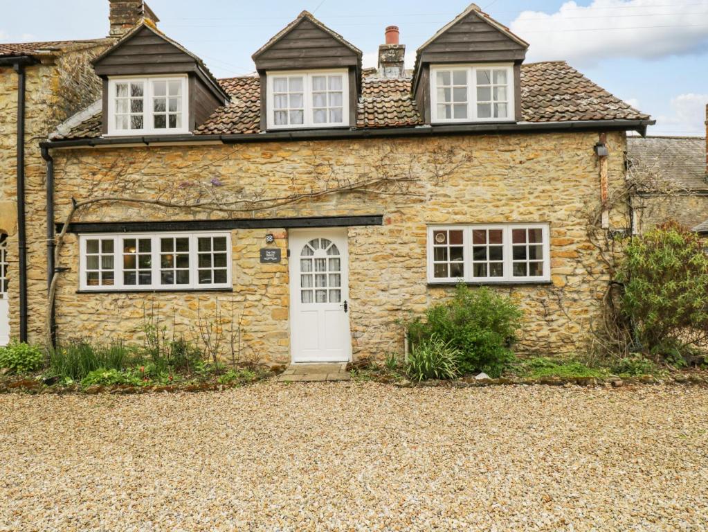 uma antiga casa de pedra com uma porta branca em The Old Bakery em Beaminster