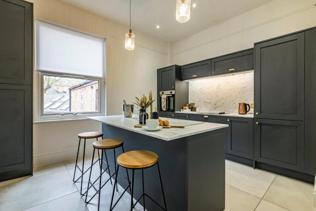 a kitchen with black cabinets and a counter with stools at 3 bed house sleeps 6 walking distance in to Nottingham city centre ideal for contractors and corporate travellers in Nottingham