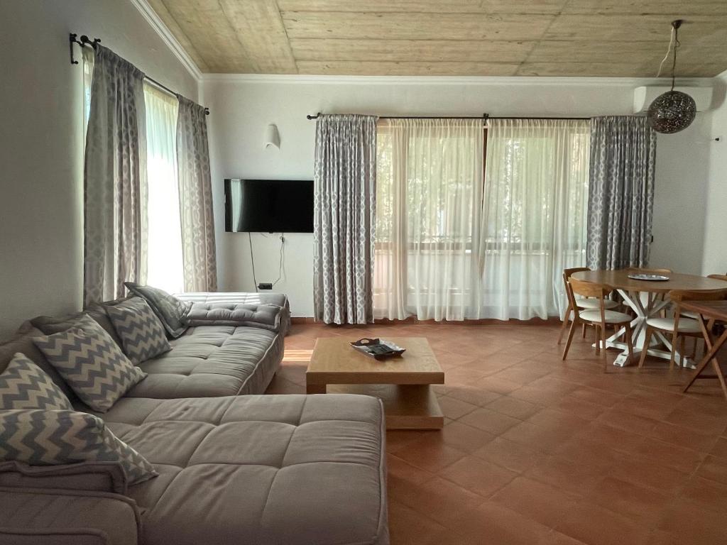 ein Wohnzimmer mit einem Sofa und einem Tisch in der Unterkunft Къща за гости “ ОАЗИС “ ет.2 in Lozenets