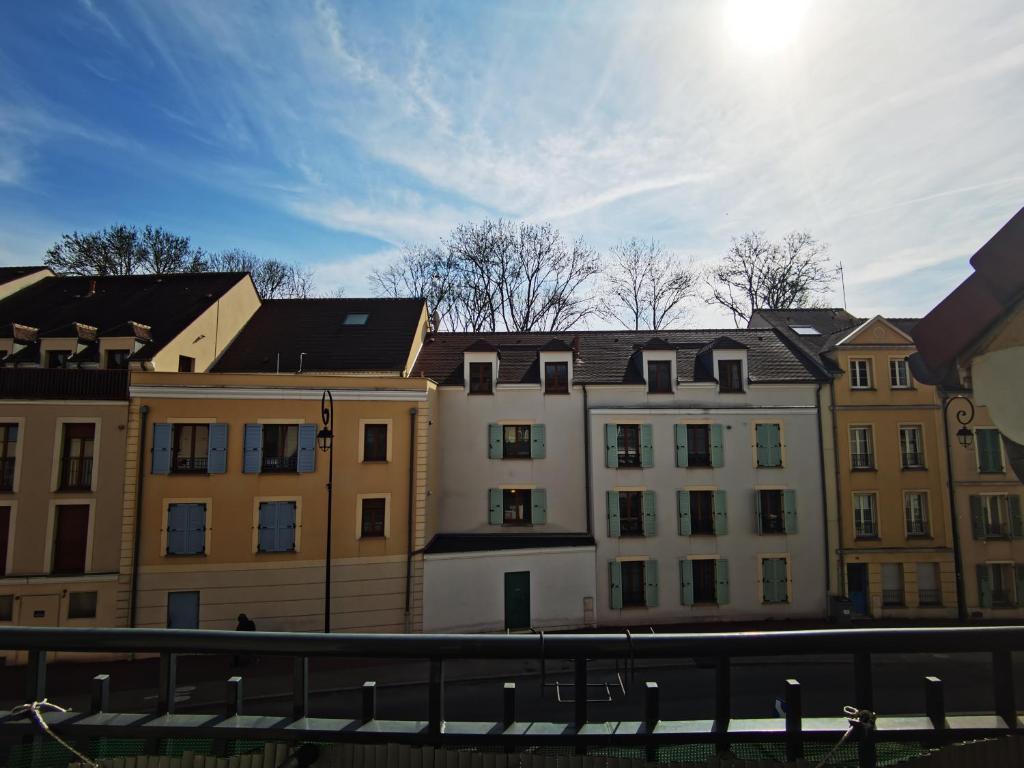 a group of buildings with the sun in the sky at Versailles Trip Appartement in Buc