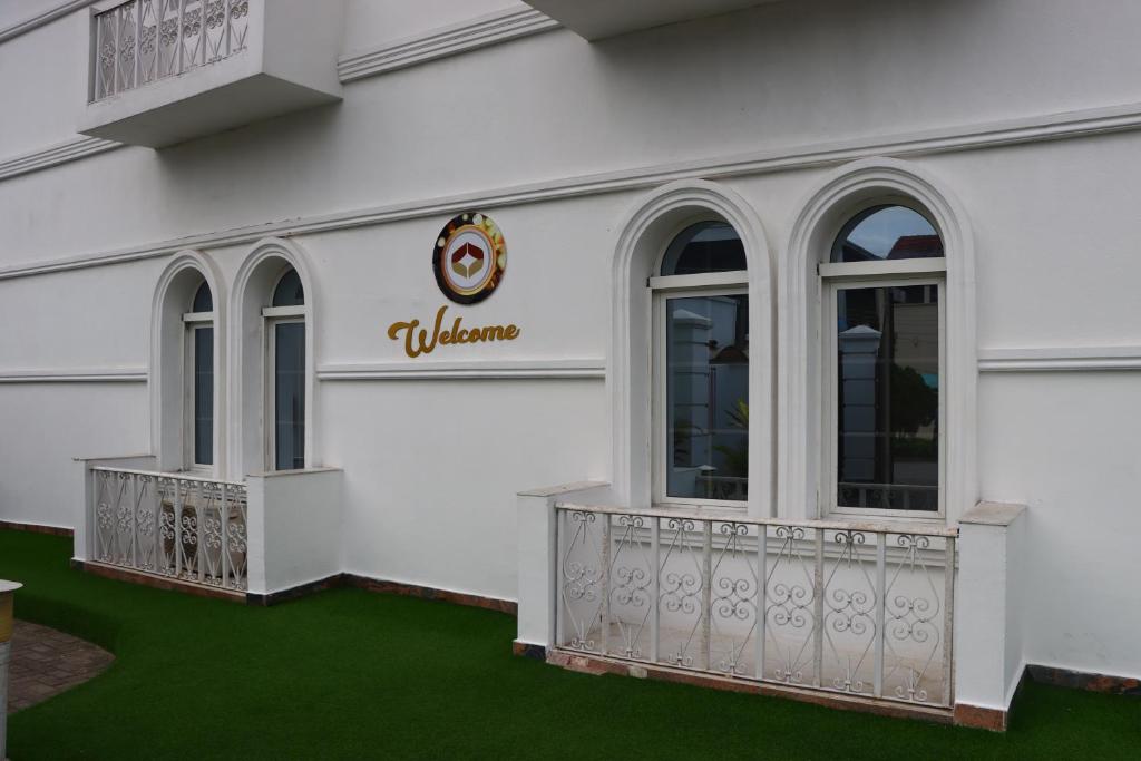 a white building with a balcony and green grass at PRESKEN WHITE HOUSE in Lagos