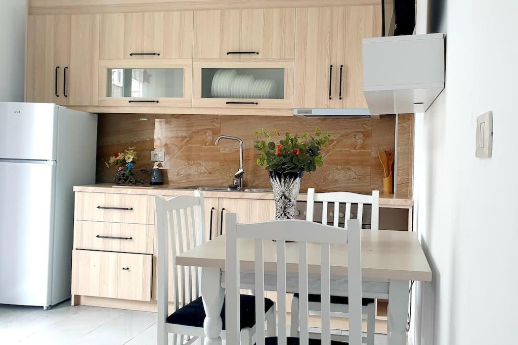a kitchen with a table and white chairs and a refrigerator at Central apartament 1 in Himare
