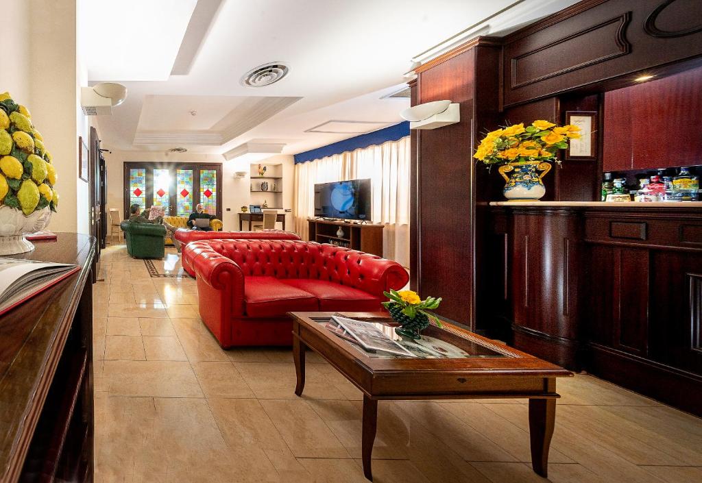 salon z czerwoną kanapą i stołem w obiekcie Hotel Sabbie d'Oro w mieście Giardini Naxos