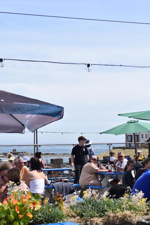 a group of people sitting at tables at the beach at The Olde Ship Inn in Seahouses