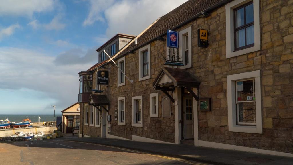 um edifício de pedra ao lado de uma rua em The Olde Ship Inn em Seahouses