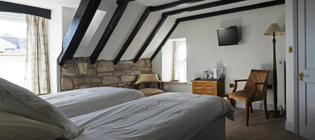a bedroom with two beds and a stone wall at The Olde Ship Inn in Seahouses