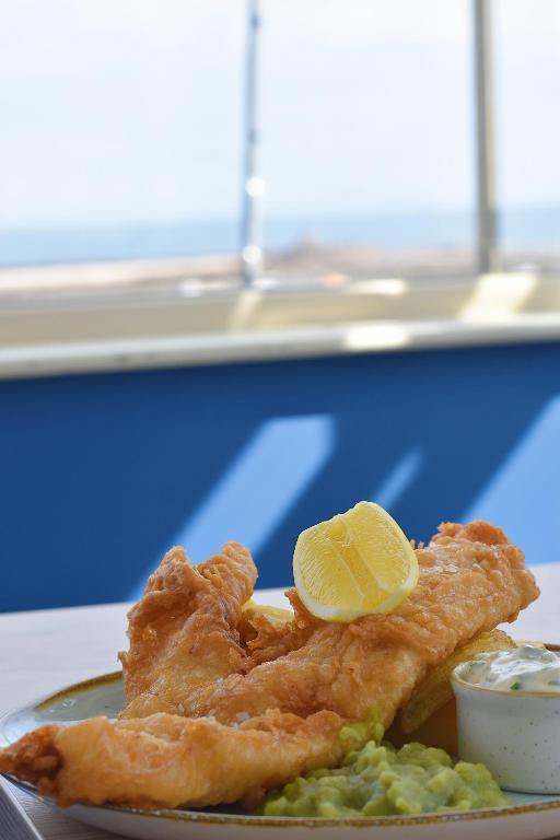 a plate of fish and chips with a lemon on it at The Olde Ship Inn in Seahouses