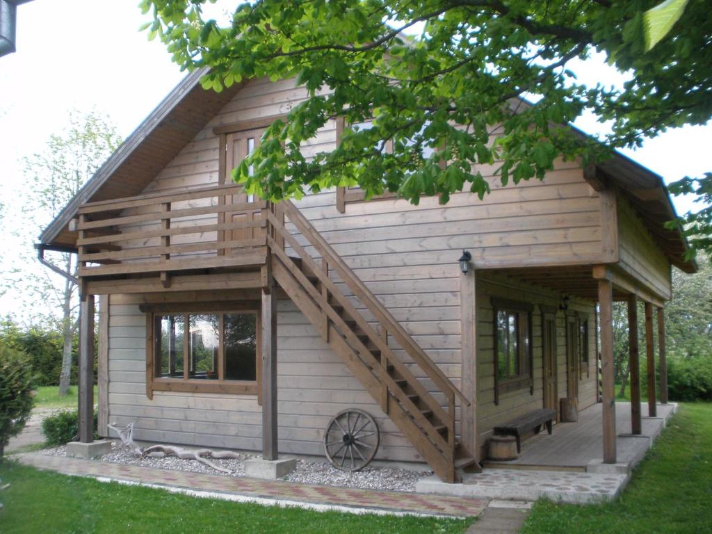 uma cabana de madeira com um alpendre e escadas em Ozoliņi em Jūrkalne