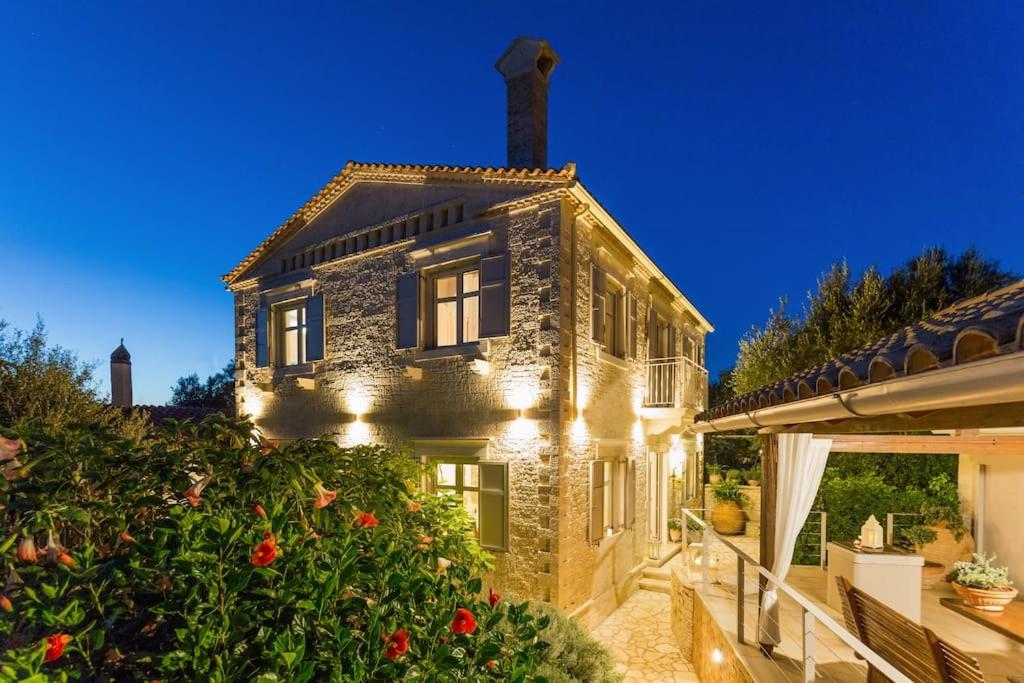 una casa de piedra con luces en el lateral. en La Maison, en Velianitátika