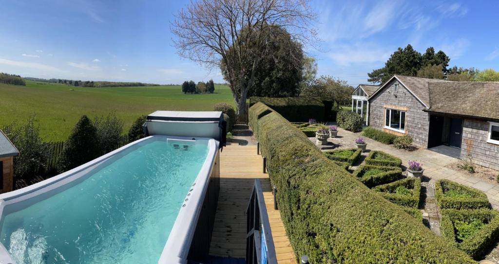 a swimming pool in a garden next to a house at Luxurious 5-Bed House with Pool, Hot Tub & Parking in Eastry
