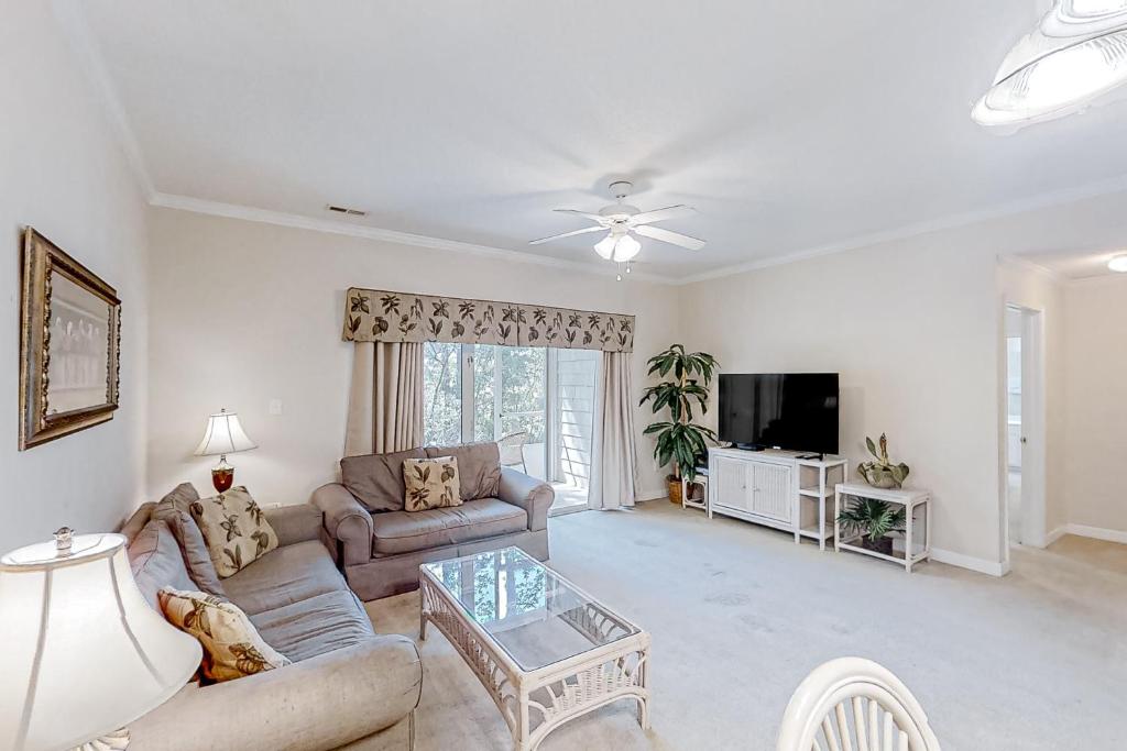 a living room with a couch and a tv at Scotch Broom I-102 in Little River