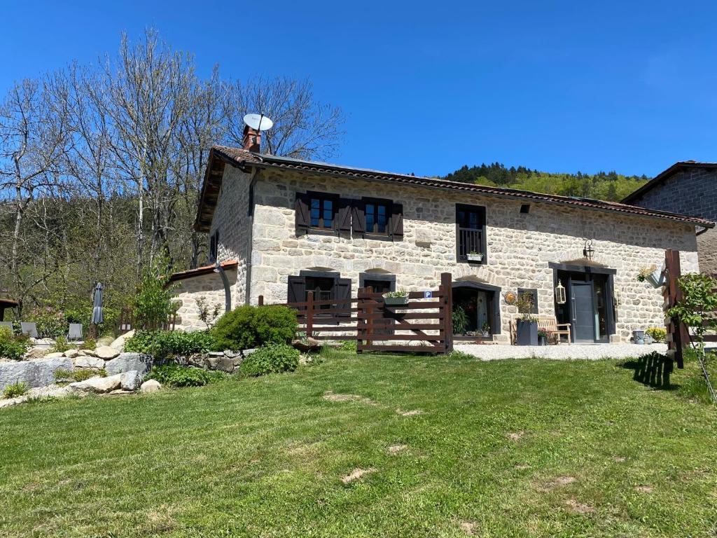 una gran casa de piedra con un campo de hierba delante de ella en La Vaisse, en Ambert