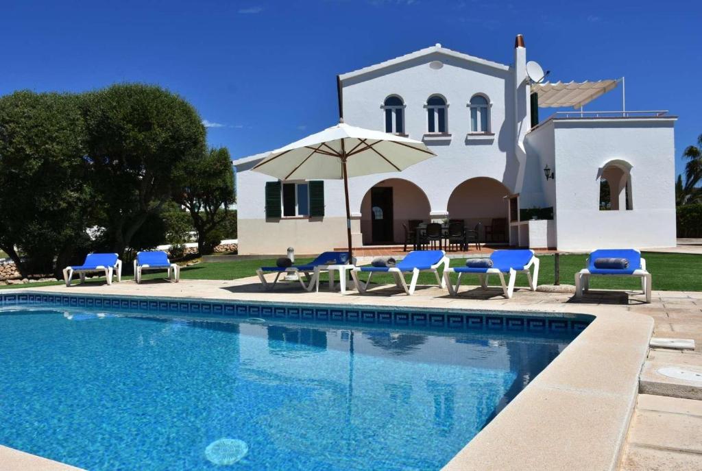 a villa with a swimming pool in front of a church at Marina in Cala en Blanes