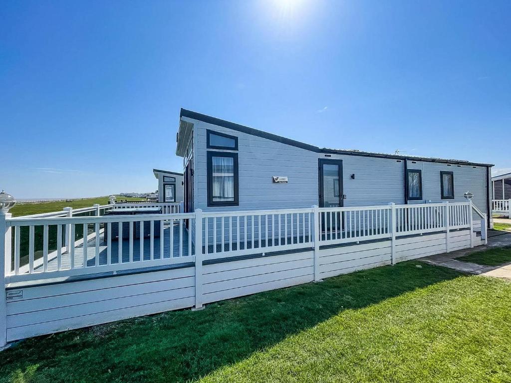 ein Haus mit einem weißen Zaun auf einem Hof in der Unterkunft Beautiful Lodge With Full Sea Views At Broadland Sands In Suffolk Ref 20235bs in Hopton on Sea