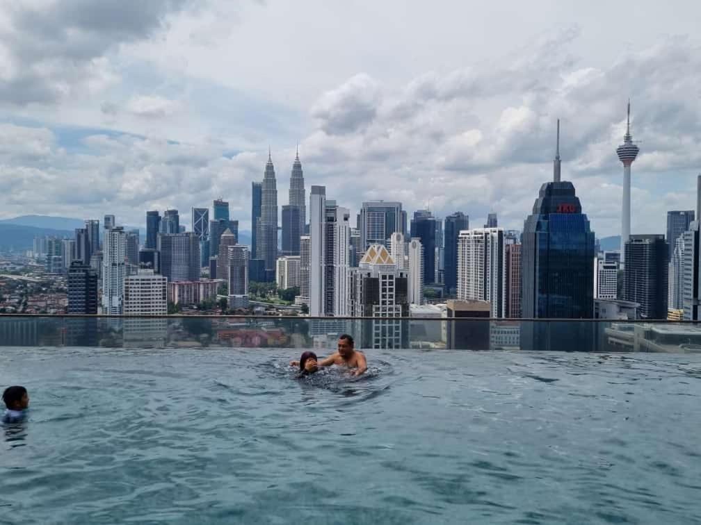 people swimming in the infinity pool on the roof of a building at Regalia Suites KL Infinity Pool _ by MygeHomes in Kuala Lumpur