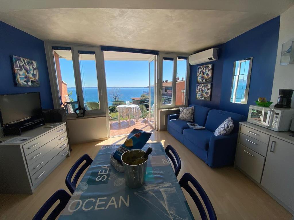 ein blaues Wohnzimmer mit einem Tisch und einem blauen Sofa in der Unterkunft Front Lake Amazing View in Manerba del Garda
