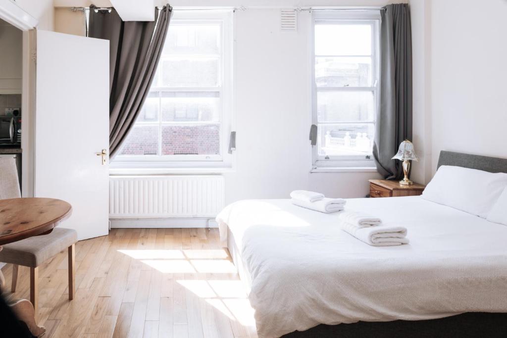 - une chambre avec un lit blanc et 2 fenêtres dans l'établissement Evelyn Court, à Londres