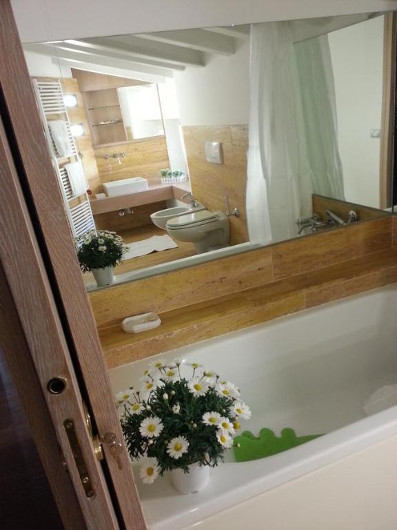 a bathroom with a mirror and a tub with flowers at B&B Bergamo Alta in Bergamo