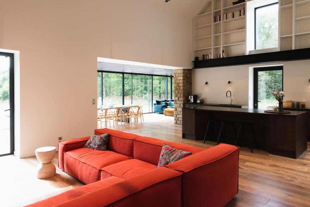 un salon avec un canapé rouge et une cuisine dans l'établissement Magnifique ferme rénovée, à La Landec