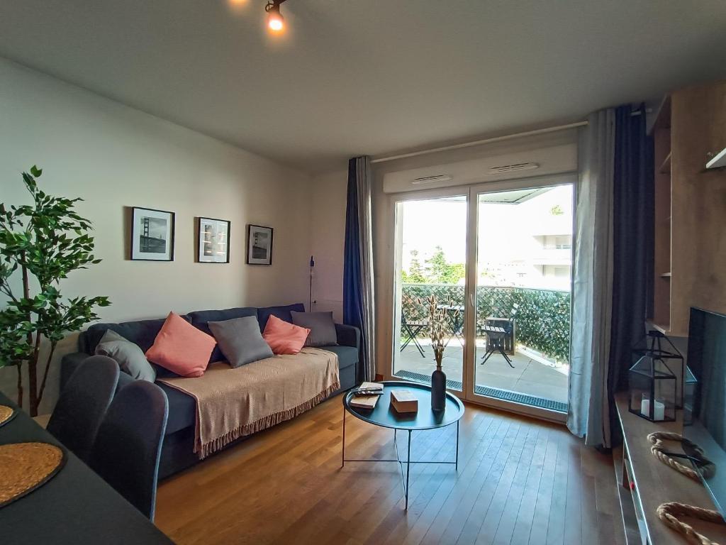 ein Wohnzimmer mit einem Sofa und einem Glastisch in der Unterkunft T3 Lumineux - Berges de la Garonne - Parking in Toulouse