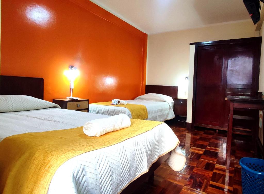 ラパスにあるHotel Expressのオレンジ色の壁のホテルルーム内のベッド2台