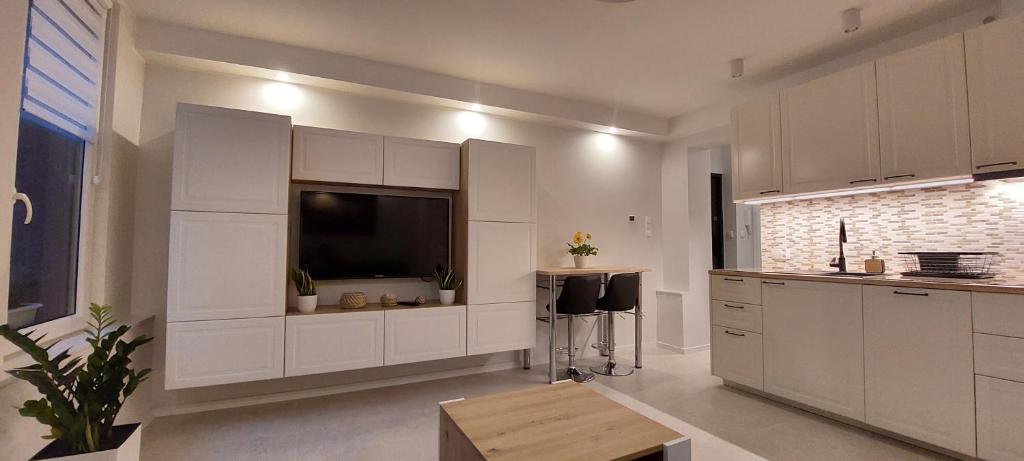 uma cozinha com armários brancos e uma televisão de ecrã plano em Apartament Akcent em Sopot
