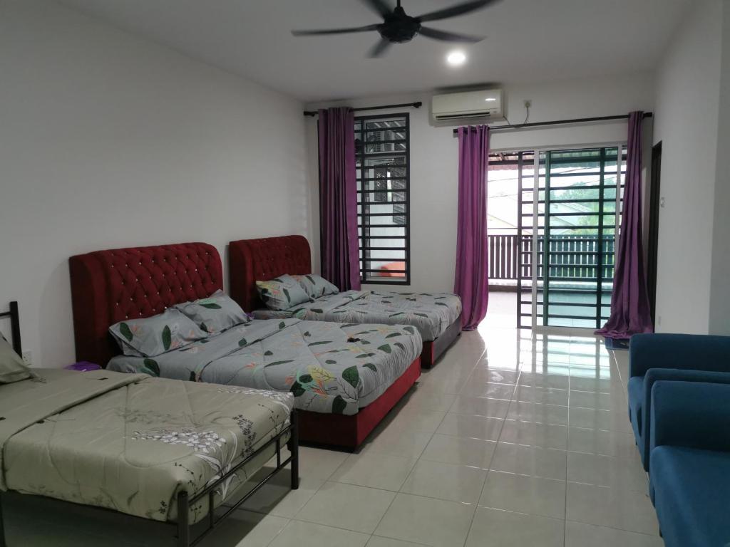 um quarto com 3 camas e uma ventoinha de tecto em cs homestay em Kuantan