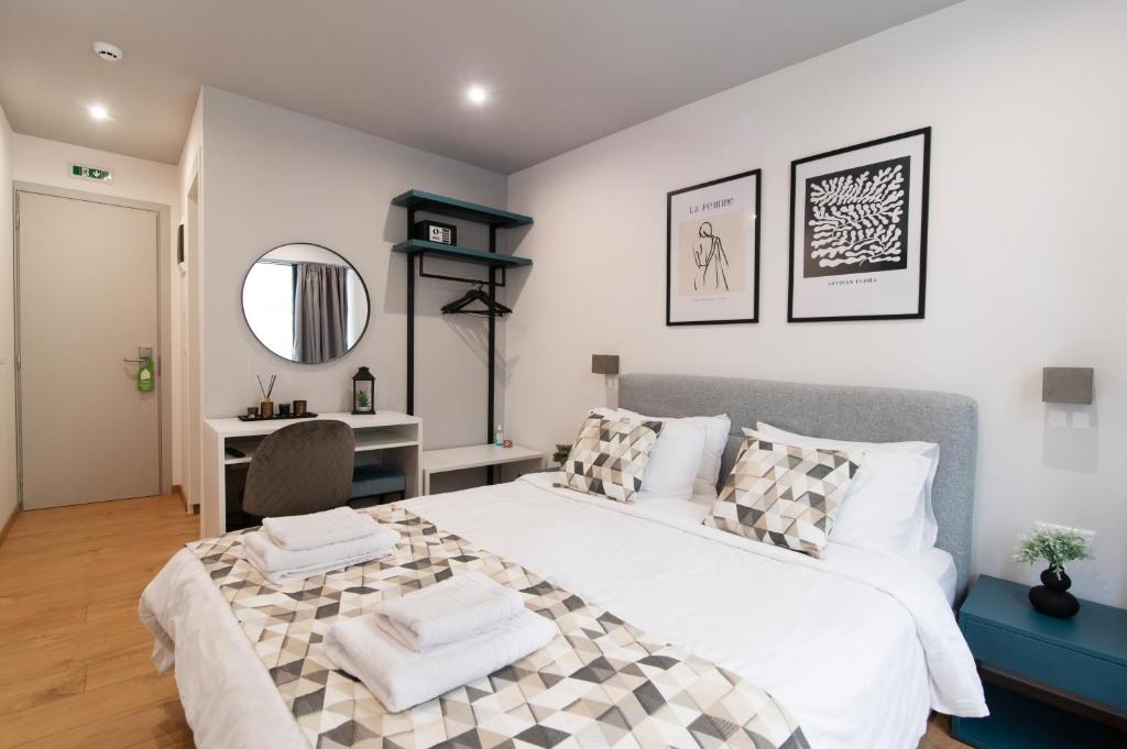una camera da letto con un grande letto bianco e una scrivania di Olvia Suites ad Atene
