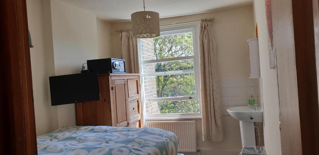 1 dormitorio con ventana, 1 cama y lavamanos en Barmy Badger Backpackers, en Londres