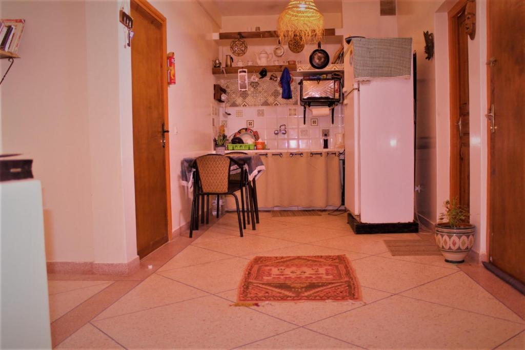 a kitchen with a refrigerator and a table with chairs at Asunfou : Appartement d'apaisement in Mirleft