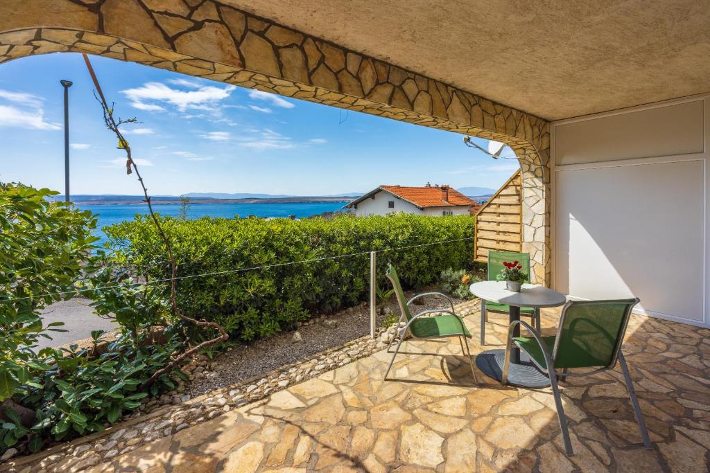 um pátio com uma mesa e cadeiras e vista para o oceano em Azalea Apartments em Dramalj