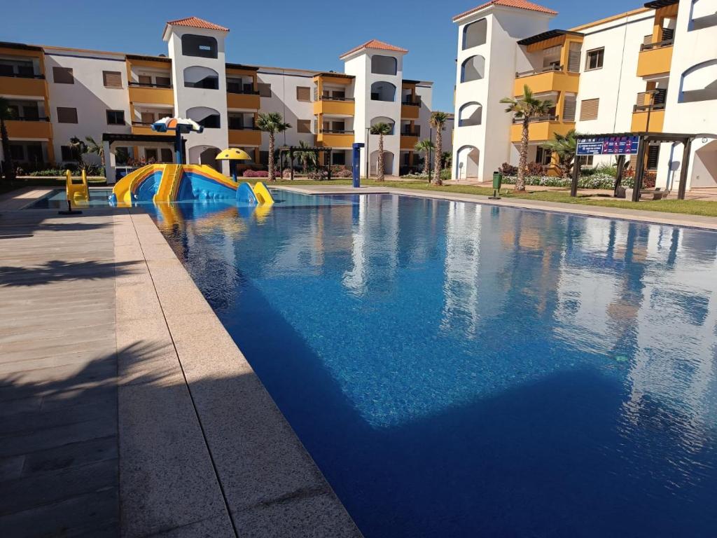 una piscina con scivolo di fronte ad alcuni edifici di Appart calme, neuf à 5mn de la plage SAADIA a Saïdia